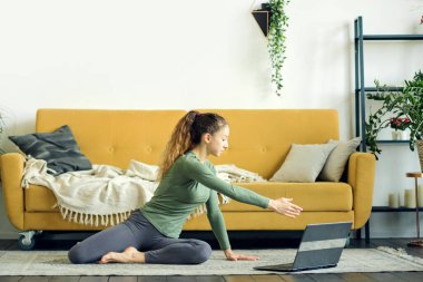 Evde yoga yapan güzel bir genç kadın. Beden eğitimi çevrimiçi.