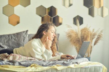 Otel odasında dizüstü bilgisayarda gülümseyen bir kadın..