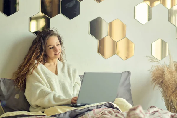 Mosolygó nő gépel laptop az ágyon a szállodai szobában. — Stock Fotó