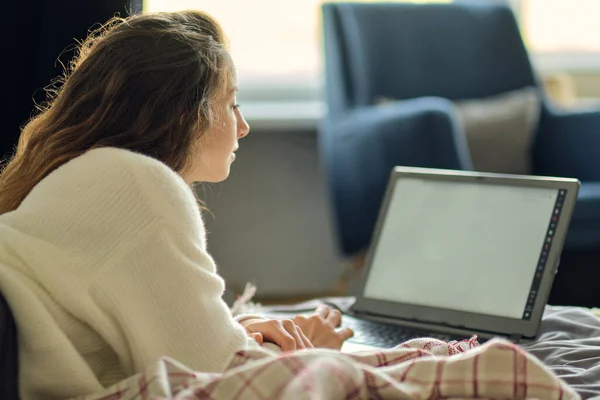 Boldog alkalmi gyönyörű nő dolgozik egy laptop ül az ágyon a házban. — Stock Fotó