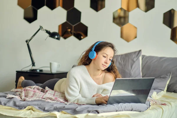 Fiatal gyönyörű nő visel headset használata közben laptop az ágyban — Stock Fotó