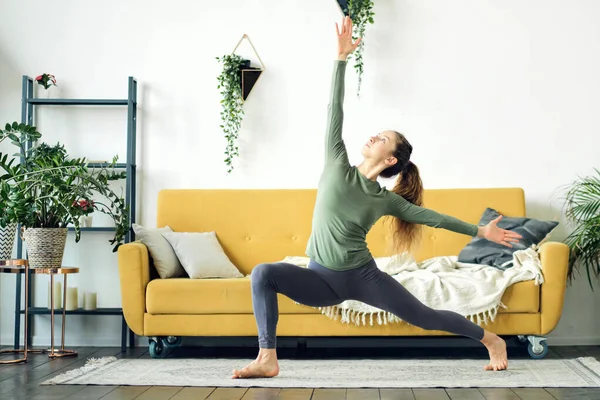 Bella giovane donna che fa yoga a casa. Allenamento fitness online. — Foto Stock