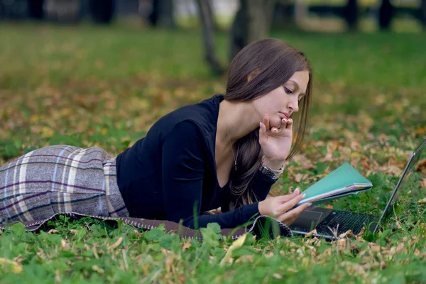 Jonge vrouw werkt voor een laptop in het park. de student bereidt zich voor op examens — Stockfoto