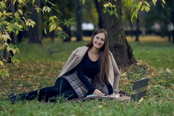 Jonge vrouw werkt voor een laptop in het park. de student bereidt zich voor op examens — Stockfoto