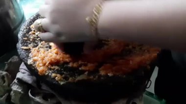 Geleneksel Endonezya yemeği olarak köri pişirmek için baharat öğüten bir kadının elleri.