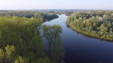 Geniş Desna nehrinin bahar manzarası. İlkbaharda geniş Desna nehrinin kuş bakışı videosu. Ağaçlar ve çalılarla çevrili. İlk yapraklar yeni çiçek açmaya başlıyor.