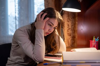 Çalışırken başını tutan yorgun bir öğrenci. Genç bir kız masada oturur ve umutsuzca başını tutar. Zor bir sorunu çözmeye çalışır.