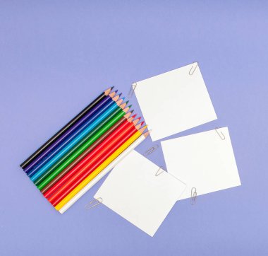 Kağıtları ve renkli kalemler Menekşe arka plan üzerinde yaprak projeleri ve Duyurular, kopya alanı için boşluklar.