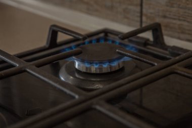 Karanlık ocakta yanan mavi gaz. Brülör gaz sobası, enerji kavramı. Portre, seçici odak.
