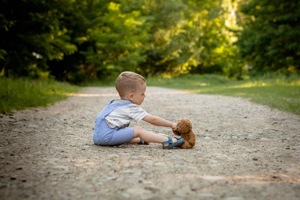 歩道でクマのぬいぐるみと遊ぶ少年 — ストック写真