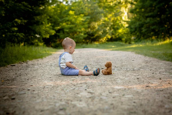 Kleiner Junge spielt mit Teddybär auf dem Fußweg — Stockfoto