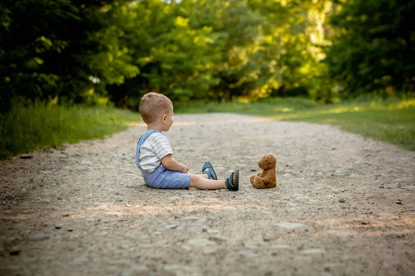 Kleiner Junge spielt mit Teddybär auf dem Fußweg — Stockfoto