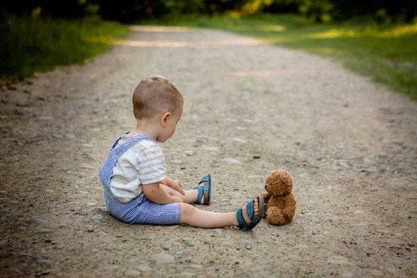 歩道でクマのぬいぐるみと遊ぶ少年 — ストック写真