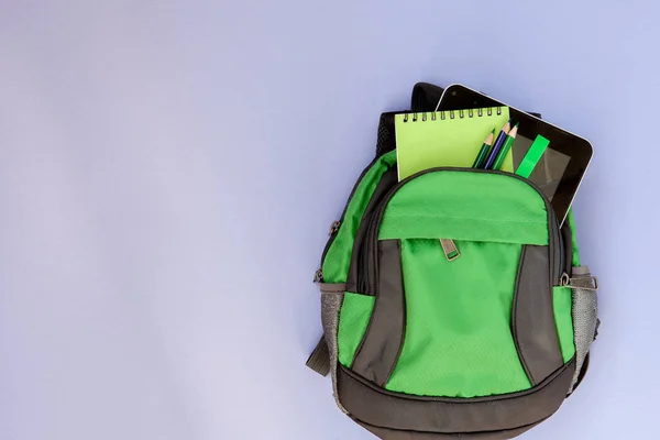 Backpack with school supplies on violet backgriond — Stock Photo, Image