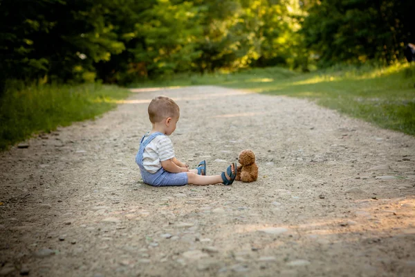 歩道でクマのぬいぐるみと遊ぶ少年 — ストック写真