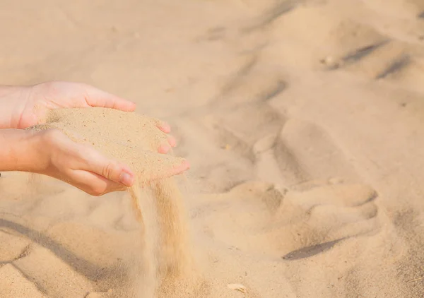 沙子流经妇女的手在海滩上 — 图库照片