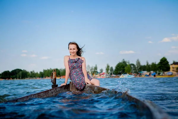 Woman sitting in an old wooden boat on a big lake Svityaz. Concept of the summer.