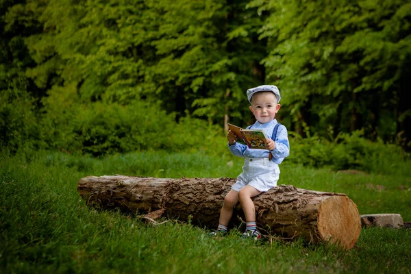 Ein Kleiner Zweijähriger Junge Sitzt Auf Einem Baum Und Liest — Stockfoto