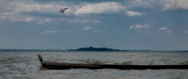 Bir gölde - bir tekne içinde oturan ve teknede ayakta su adlı iki martı.