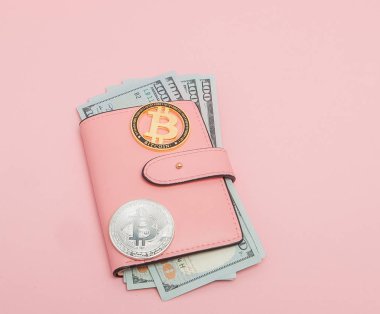 Pembe arka planda fotokopi alanı olan pembe bir cüzdanda Bitcoin ve dolar.