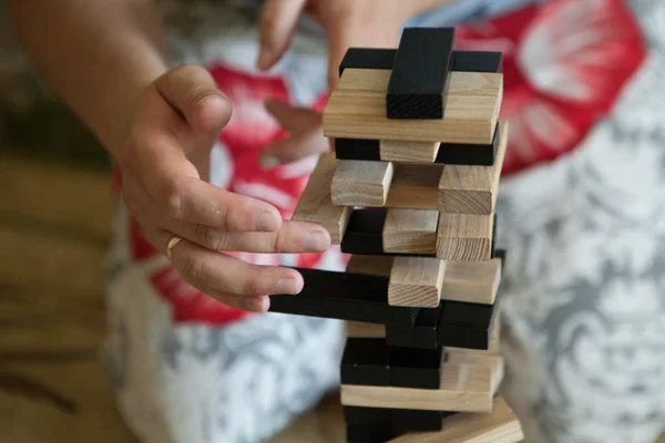 Man playing with the wood game jenga at home. Concept of education, risk, development, and growth.