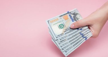 Doları s banknotlar kopya alanı ile pembe arka plan üzerinde kadın elinde yığını.