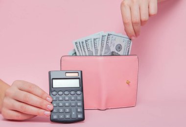 Arka plan kopya alanı ile pembe arka plan üzerinde cüzdanından para kaldırma kadın eli ile hesap makinesi.