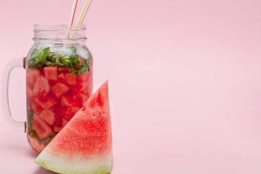 Dilim meyve ve pembe bir arka plan üzerine nane yaprağı ile karpuz güler yüzlü.