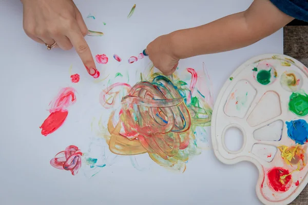 Boyalı elleriyle resim yapan sevimli küçük bir çocuk beceriksizce resim yapıyor..