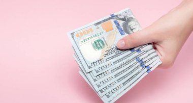 Doları s banknotlar kopya alanı ile pembe arka plan üzerinde kadın elinde yığını.