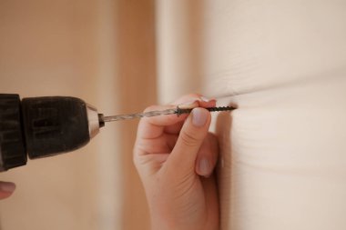 Yakın çekim vida ve elektrikli tornavida tutan kadın.