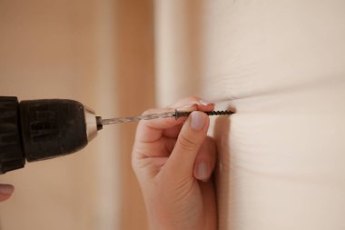 Yakın çekim vida ve elektrikli tornavida tutan kadın.