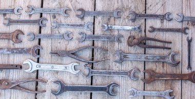 Siyah ahşap masanın üzerinde yatan metal anahtarı paslı araçları. Çekiç, keski, demir testeresi, metal anahtarı. Kirli ahşap panel antika arka plan üzerinde el aletleri ile bir araçlar kümesi