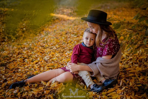 Šťastná mladá matka hraní s dítětem v podzimním parku s žluté maple listy. Rodinné procházky venku na podzim. Malý chlapec se svou matkou hraje v parku na podzim — Stock fotografie