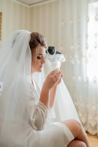 A noiva encantadora com damas de honra fica perto do vestido de noiva. Preparação da manhã do casamento nupcial — Fotografia de Stock