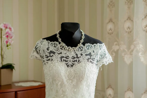 an elegant wedding dress on a mannequin in a beautiful light room.