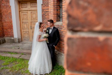 güzel düğün çift koca takım elbise ve karısı tuğla duvara yakın poz gelinlik.