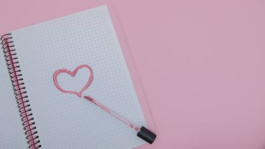 Kalp bir ruj pembe bir arka plan üzerinde bir defter ile boyanmıştır. Aşk ve güzellik kavramı.