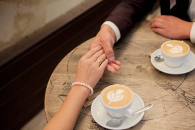 Gelin ve damat fincan cappuccino ile tutun ve birbirinize bakın.