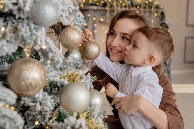 Anne ve küçük oğlu oyuncaklar ve çelenk ile Noel ağacı süsleme.