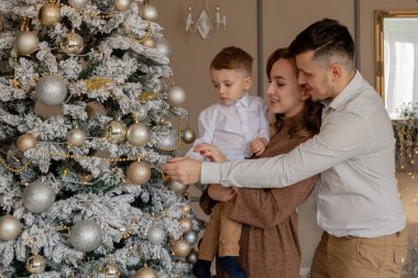 Anne ve küçük oğulları oyuncaklar ve çelenk ile Noel ağacı süsleme.