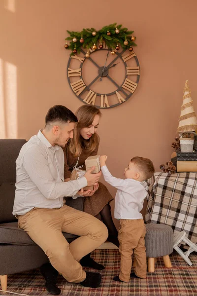 Little boy gives parents a gift box. Birthday gifts . Little son with his family. Holidays, present, childhood, happiness concept. Little boy celebrating birthday with his parents.