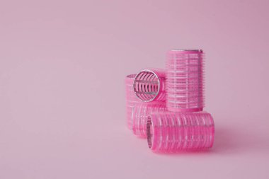 Curlers saç plastik kopya alanı ile pembe bir arka plan üzerinde.
