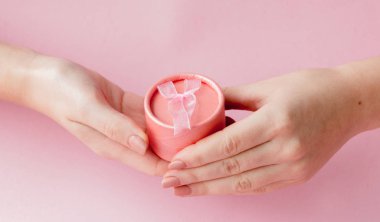 Kadın yuvarlak pembe hediye kutusunda bir pembe eller. Sevgililer günü, anneler günü veya Doğum günü için festival kavramı.