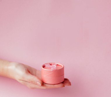 Kadın yuvarlak pembe hediye kutusunda bir pembe eller. Sevgililer günü, anneler günü veya Doğum günü için festival kavramı.