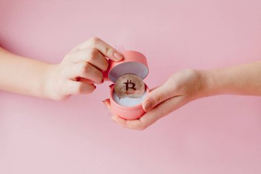 Pembe bir arka plan, sanal para simgesi pembe hediye kutusunda Bitcoin holding kadının eller.