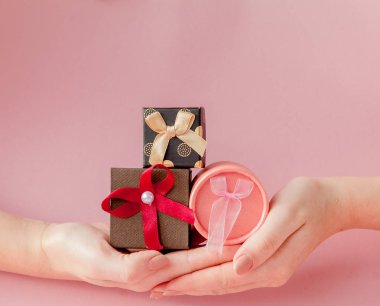 Kadınların elleri pembe bir arka plan üzerinde küçük hediye kutuları. Sevgililer günü, anneler günü veya Doğum günü için festival kavramı.