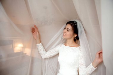 Gelin sabah hazırlık. Güzel gelin yatak odası penceresinin yakınındaki beyaz düğün sabahlık.