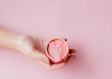Kadın yuvarlak pembe hediye kutusunda bir pembe eller. Sevgililer günü, anneler günü veya Doğum günü için festival kavramı.