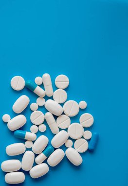 Mavi masaya saçılmış beyaz haplar. Reklam, web geçmişi ya da diğer fikirler için özel teklifler alın. Tıbbi, eczane ve sağlık hizmetleri konsepti. Uzayı kopyala Metin veya logo için boş yer.